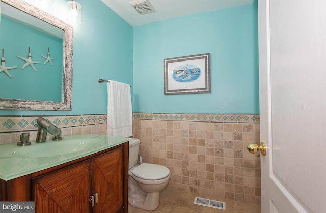 bathroom featuring tile patterned flooring, vanity, tile walls, and toilet