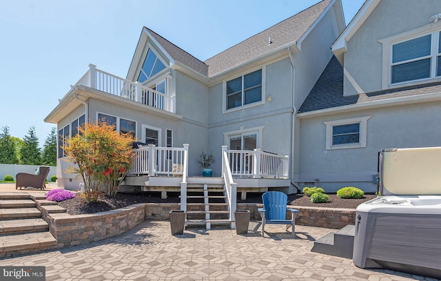 back of house with a balcony, a patio, a wooden deck, and a hot tub