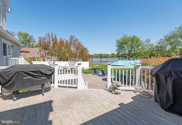 wooden terrace featuring area for grilling and a water view