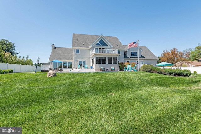 rear view of property with a lawn, a patio area, and a balcony