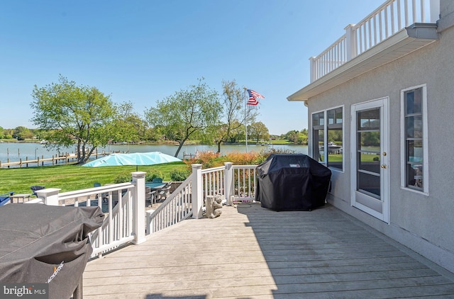 deck with grilling area, a yard, and a water view