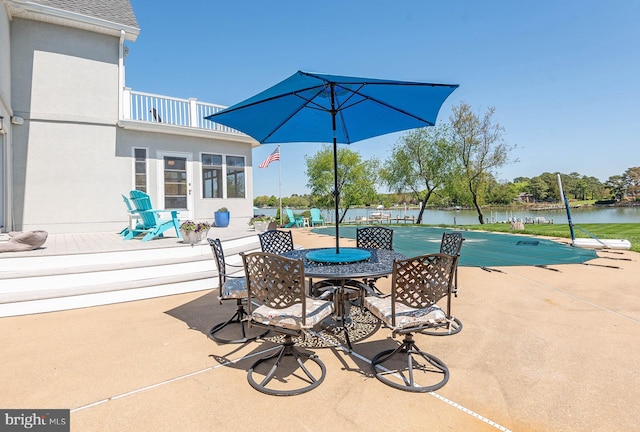 view of patio featuring a water view, a balcony, and a pool