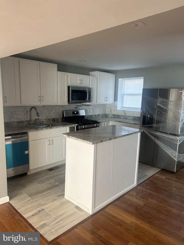 kitchen featuring white cabinets, a center island, light hardwood / wood-style flooring, and stainless steel appliances