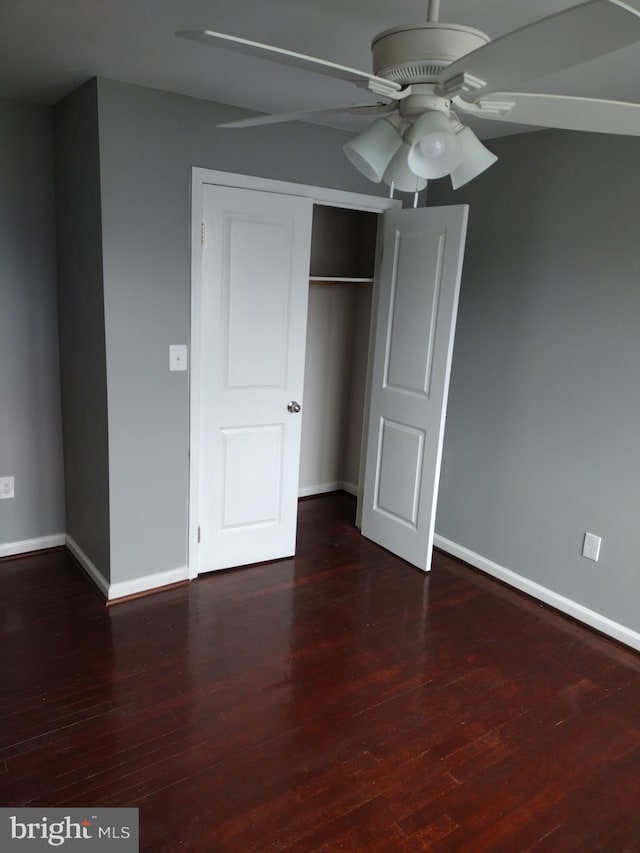 unfurnished bedroom featuring ceiling fan, a closet, and dark wood-type flooring