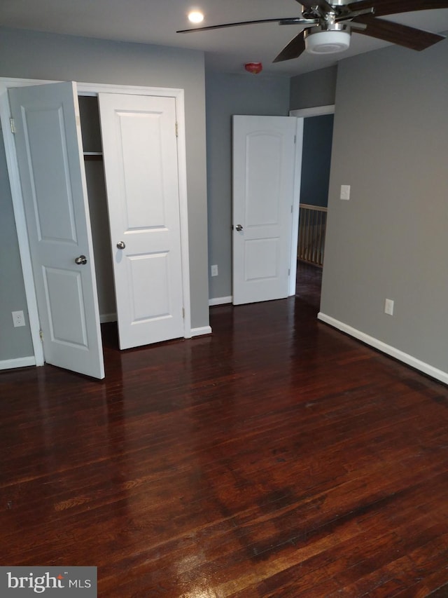 unfurnished bedroom featuring ceiling fan, a closet, and dark wood-type flooring