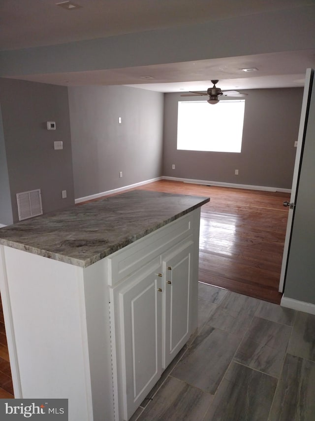 kitchen featuring hardwood / wood-style flooring, stone countertops, ceiling fan, and white cabinetry