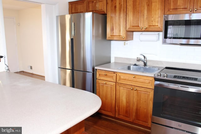 kitchen featuring sink, stainless steel appliances, tasteful backsplash, and dark wood-type flooring