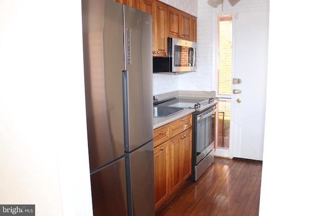 kitchen featuring dark hardwood / wood-style flooring, backsplash, and appliances with stainless steel finishes