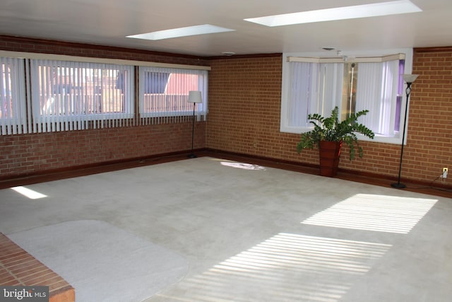 carpeted empty room featuring a skylight and brick wall