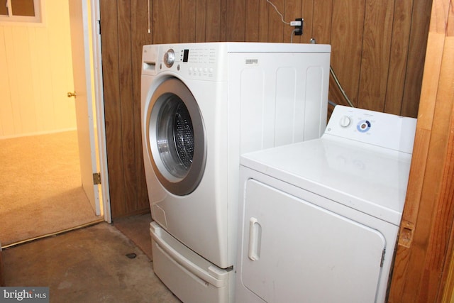 washroom featuring wood walls and washing machine and dryer