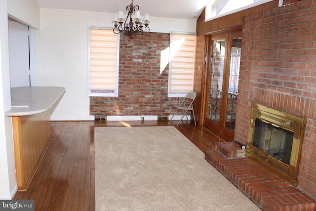 living room featuring a chandelier, a brick fireplace, vaulted ceiling, and dark hardwood / wood-style floors