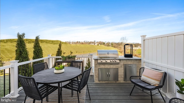 wooden terrace featuring grilling area, a rural view, and exterior kitchen