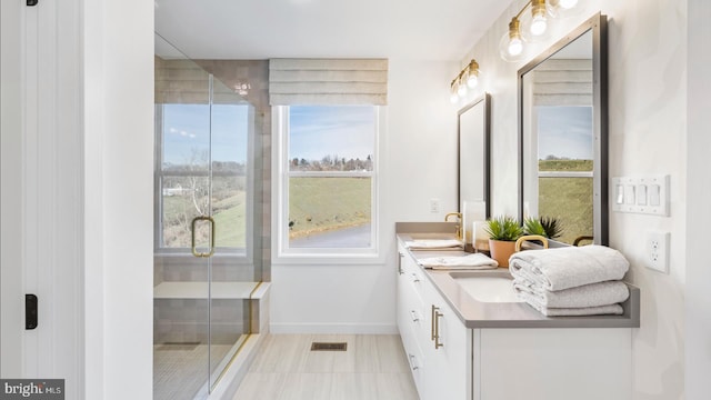 bathroom with a shower with shower door, tile floors, and dual bowl vanity