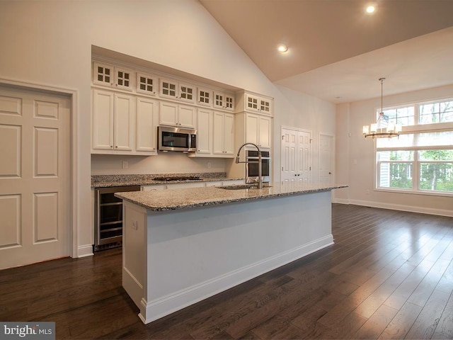 kitchen with decorative light fixtures, high vaulted ceiling, dark wood-type flooring, sink, and an island with sink