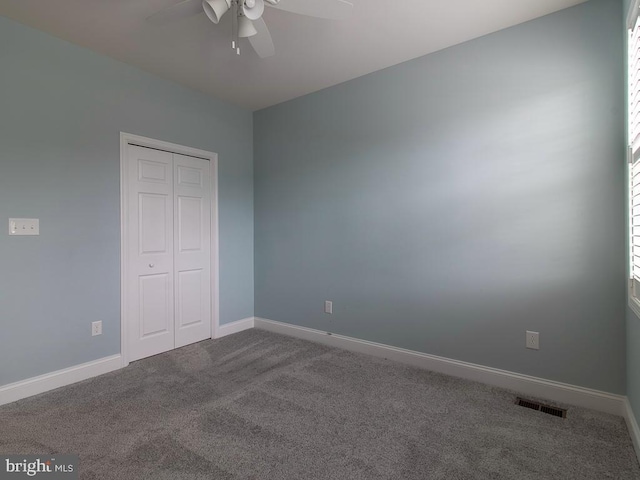 unfurnished bedroom featuring a closet, ceiling fan, and dark carpet