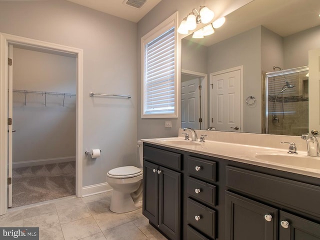 bathroom featuring toilet, an enclosed shower, tile floors, and double vanity