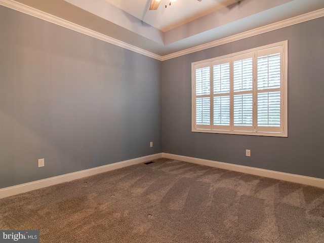 empty room with ceiling fan, dark carpet, and a tray ceiling