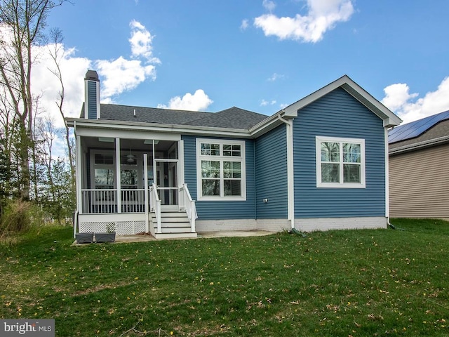 back of house featuring solar panels, a sunroom, and a lawn