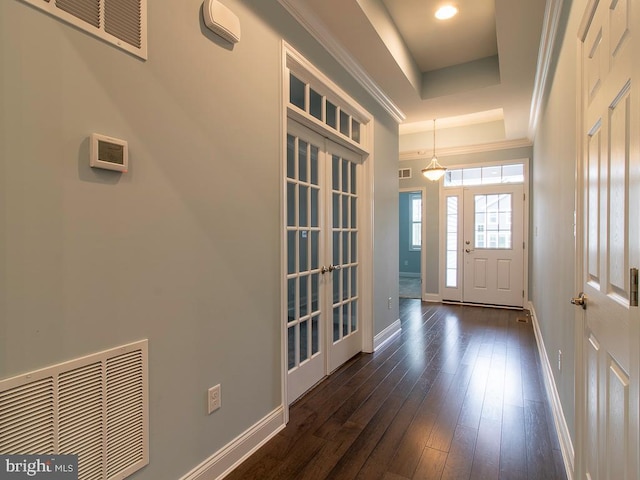 entryway featuring crown molding, a tray ceiling, and dark wood-type flooring