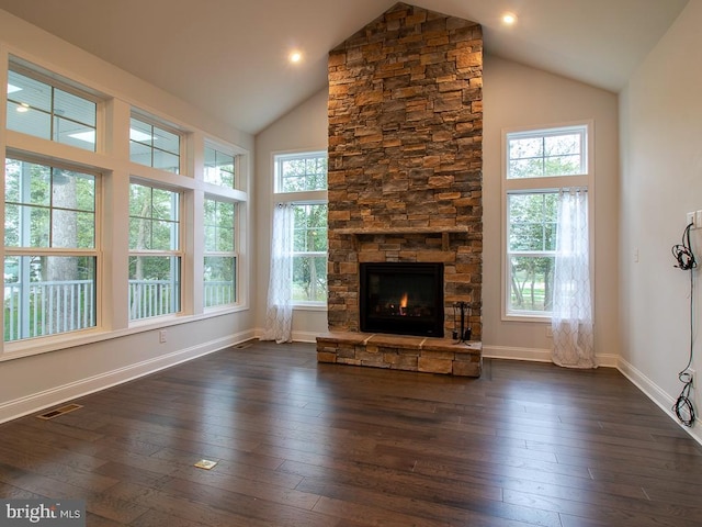 unfurnished living room with a wealth of natural light, a stone fireplace, and dark wood-type flooring