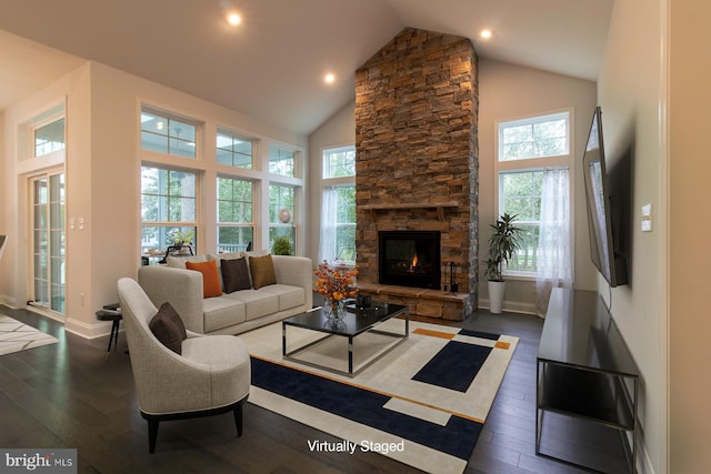 living room with high vaulted ceiling, a healthy amount of sunlight, a stone fireplace, and dark wood-type flooring