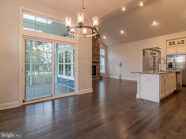 kitchen featuring hanging light fixtures, a kitchen island with sink, dark wood-type flooring, light stone counters, and white cabinets