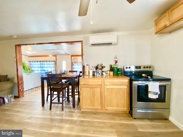 kitchen featuring a wall unit AC, stainless steel electric range, ceiling fan, and light hardwood / wood-style flooring