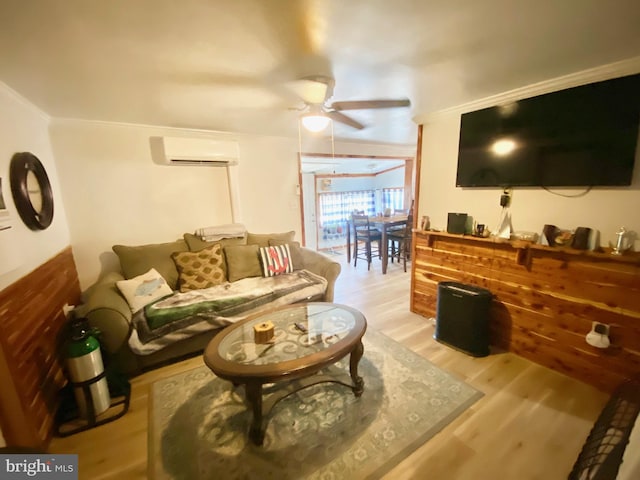 living room featuring ceiling fan, an AC wall unit, light hardwood / wood-style flooring, and crown molding