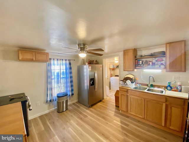 kitchen featuring ceiling fan, stainless steel fridge, washer / dryer, light hardwood / wood-style floors, and sink