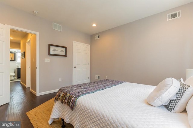 bedroom with ensuite bath and dark hardwood / wood-style flooring