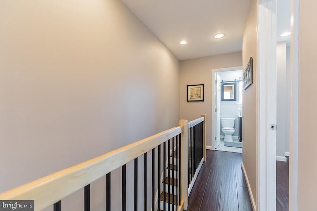 hall featuring a barn door and dark wood-type flooring