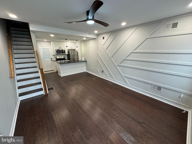 unfurnished living room featuring dark hardwood / wood-style flooring and ceiling fan