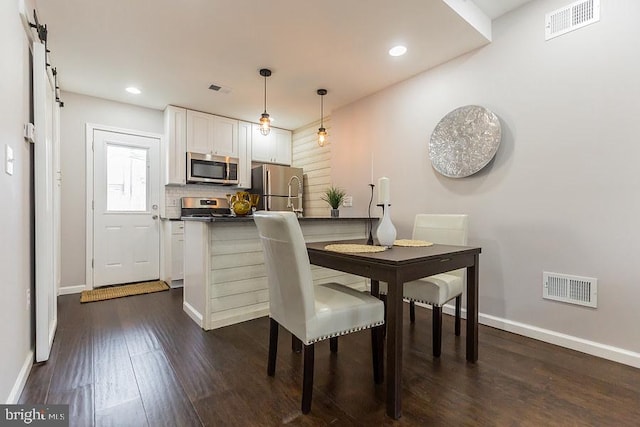 dining space with a barn door and dark hardwood / wood-style flooring