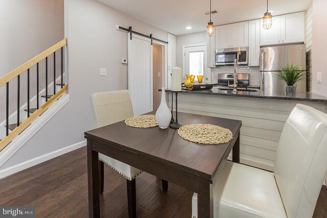 dining room with a barn door, dark wood-type flooring, and sink