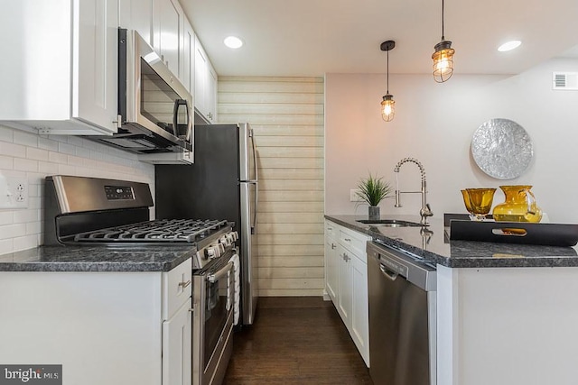 kitchen featuring dark hardwood / wood-style floors, sink, stainless steel appliances, white cabinets, and pendant lighting