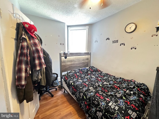 bedroom with ceiling fan, a textured ceiling, and light hardwood / wood-style flooring