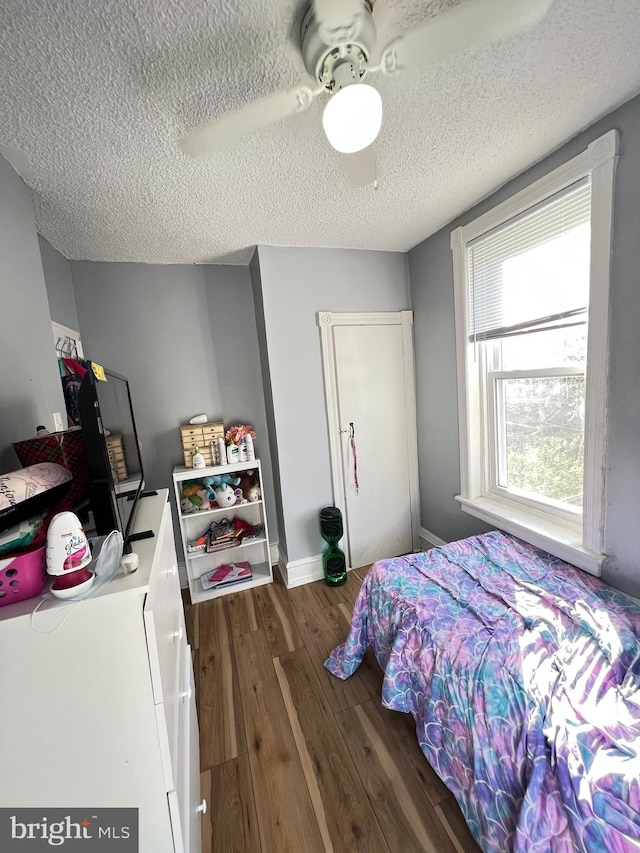 bedroom featuring a textured ceiling, dark hardwood / wood-style floors, and ceiling fan