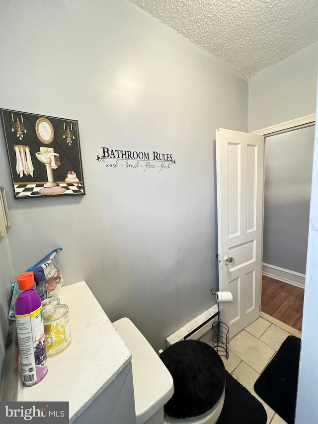 bathroom with baseboard heating, a textured ceiling, tile flooring, and vanity