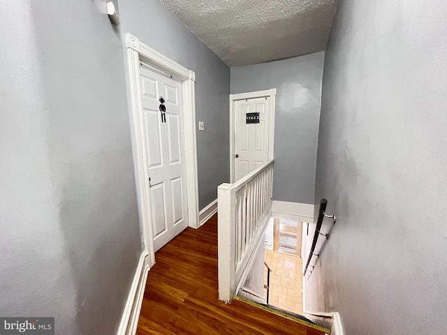 stairway featuring a textured ceiling and dark hardwood / wood-style flooring