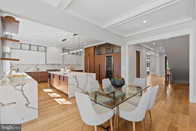 dining room featuring crown molding, light wood-type flooring, and sink