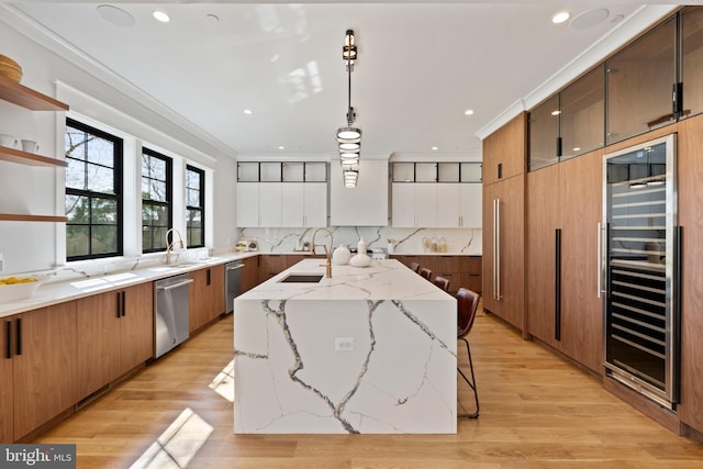 kitchen with decorative light fixtures, light wood-type flooring, an island with sink, beverage cooler, and stainless steel dishwasher