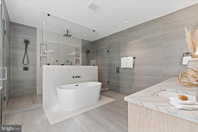 bathroom featuring tile flooring, tile walls, and plus walk in shower