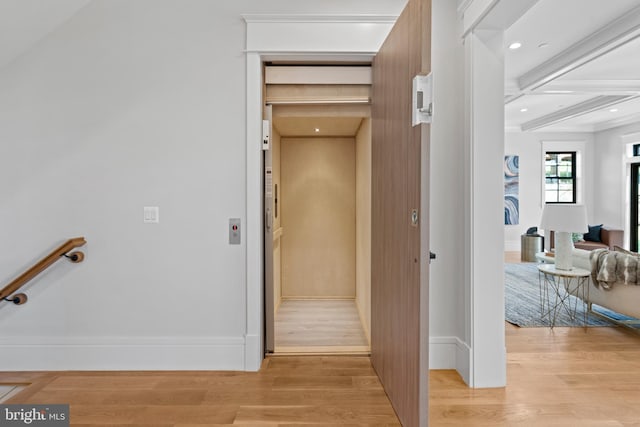 corridor featuring elevator, coffered ceiling, beam ceiling, and light wood-type flooring