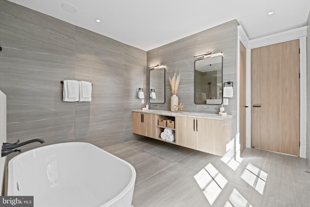 bathroom featuring tile walls, double vanity, a washtub, and tile flooring