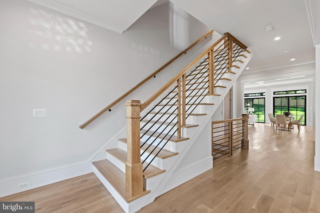 stairway featuring light hardwood / wood-style flooring and ornamental molding