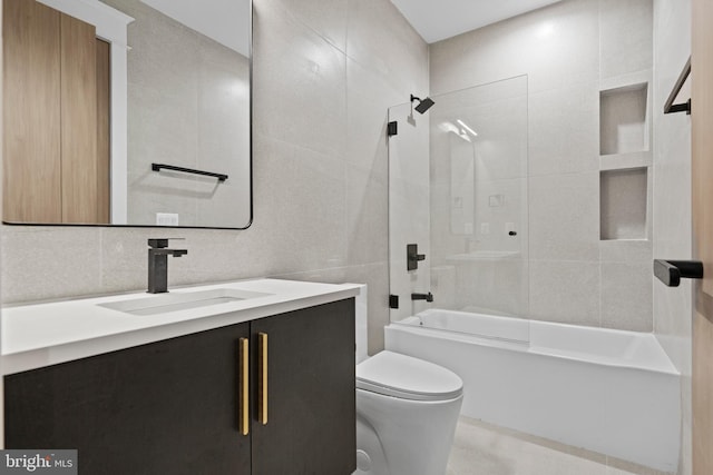 full bathroom featuring tile walls, toilet, oversized vanity, and tiled shower / bath