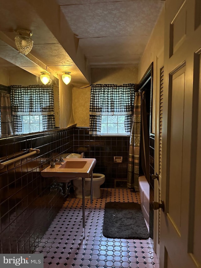 full bathroom with tile walls, backsplash, shower / bath combo, toilet, and tile floors