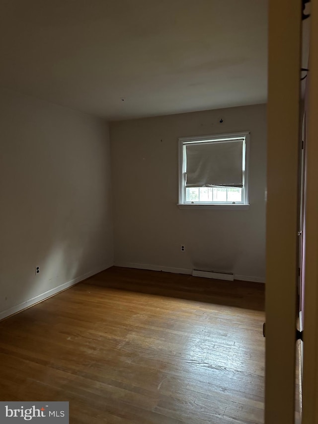 empty room with baseboard heating and light hardwood / wood-style floors