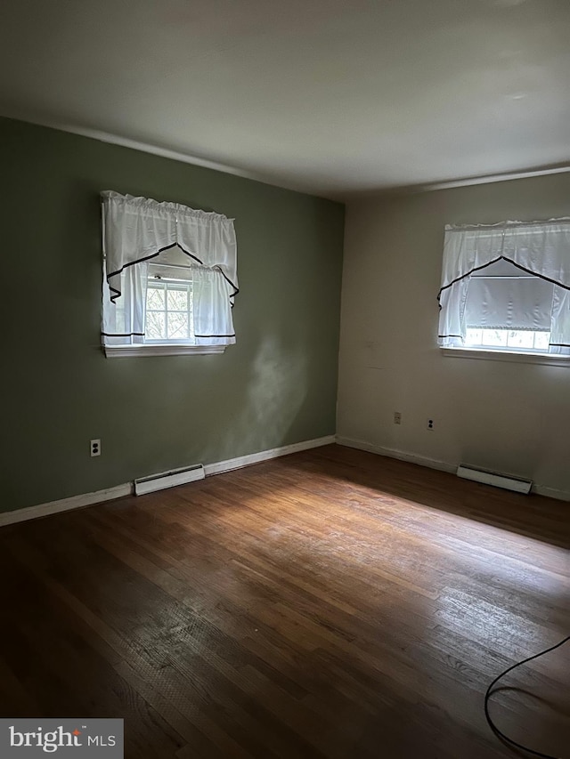 empty room with hardwood / wood-style flooring and a baseboard radiator