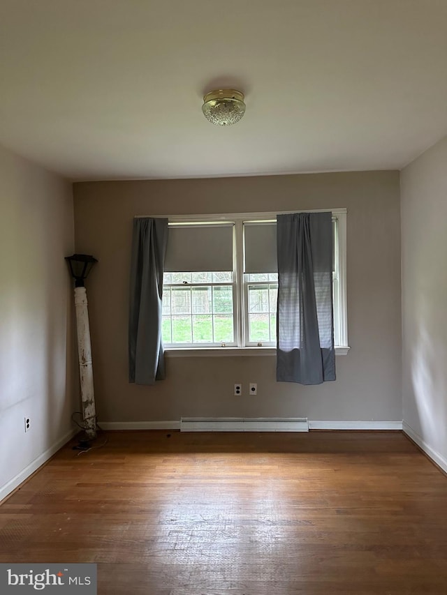 empty room with wood-type flooring and a baseboard radiator